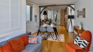 Un salon moderne avec un plafond en briques, un coin repas et une cuisine à l’arrière-plan.