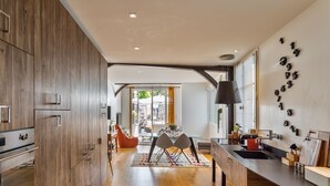 Une cuisine moderne avec des meubles en bois, un coin repas doté d’une table et de chaises en verre, et un îlot de cuisine avec un évier et un plan de travail.