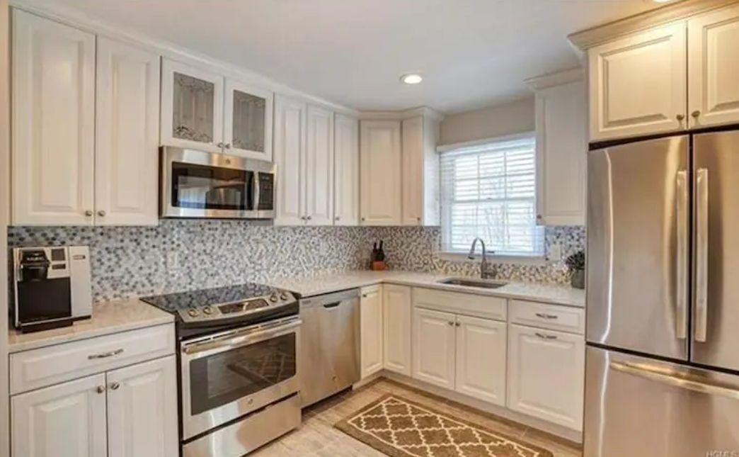 A kitchen with white cabinets, stainless steel appliances, a microwave, oven, and a refrigerator.