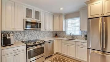 A kitchen with white cabinets, stainless steel appliances, a microwave, oven, and a refrigerator.