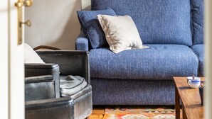 A room with a blue sofa, a small table with a cup, and a wall-mounted light fixture. - Le Traou Mad - Au cœur de l'Intra-muros (Saint-Malo)