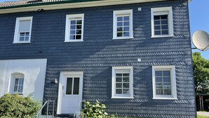 A two-story house with a dark blue exterior, white trim, and a satellite dish. - Ferienwohnung in Sehr Ruhiger, Idyllischer Lage (Hückeswagen)