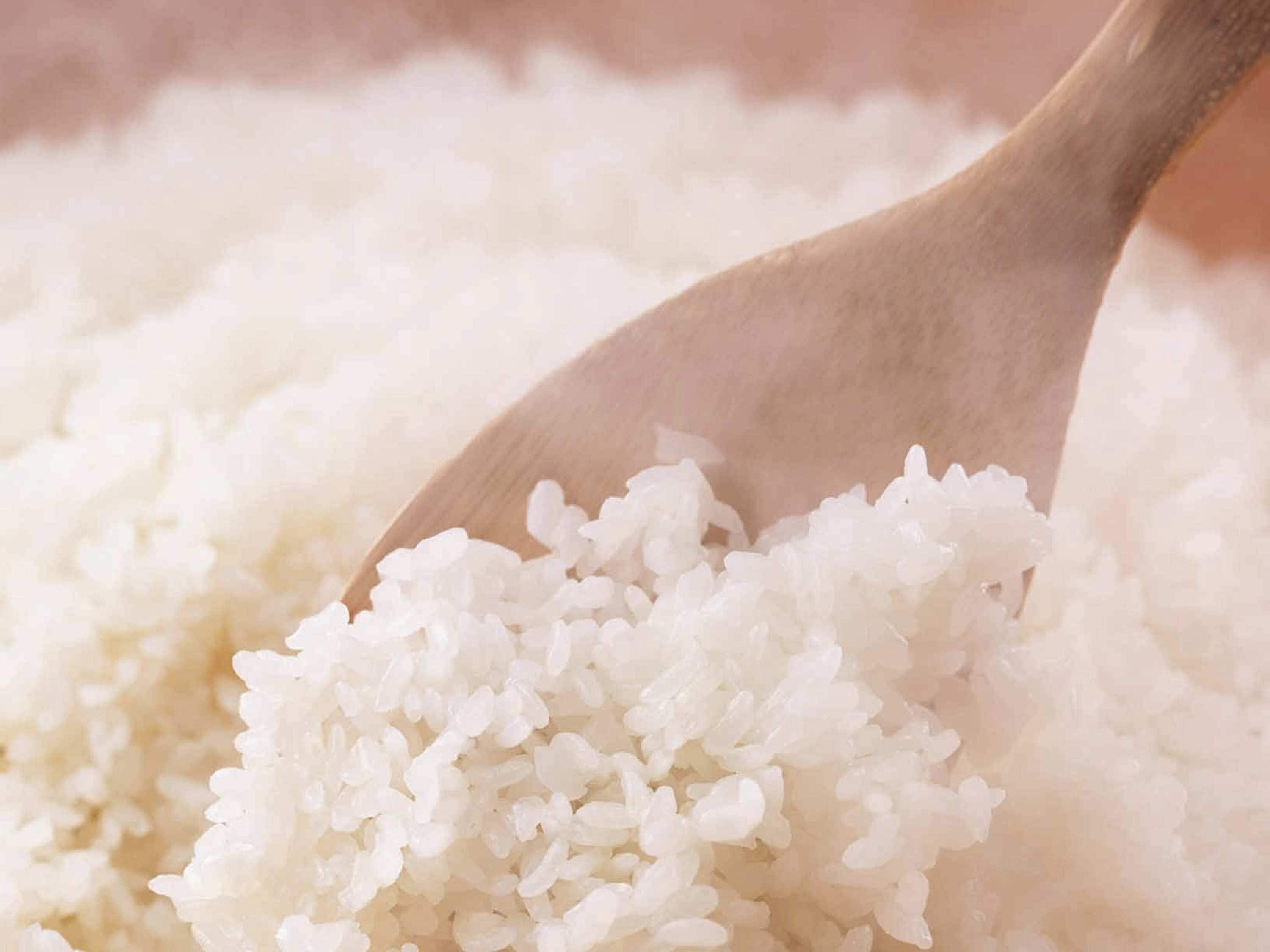Une cuillère en bois remplie de riz blanc.