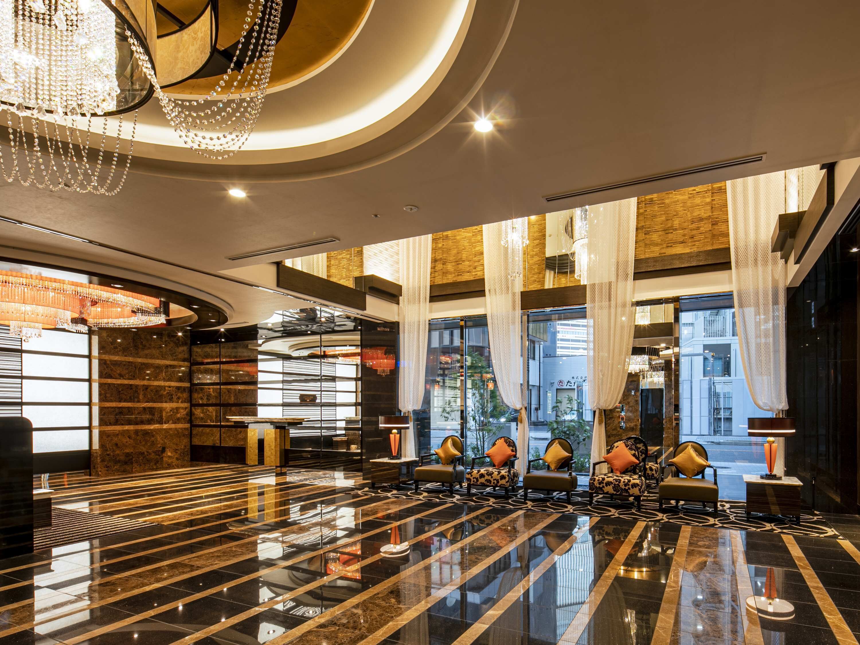 A luxurious lobby with a polished marble floor, elegant seating, and a grand chandelier.