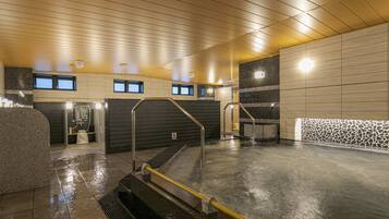 A modern indoor pool area with a wet floor, tiled walls, and a wooden ceiling.