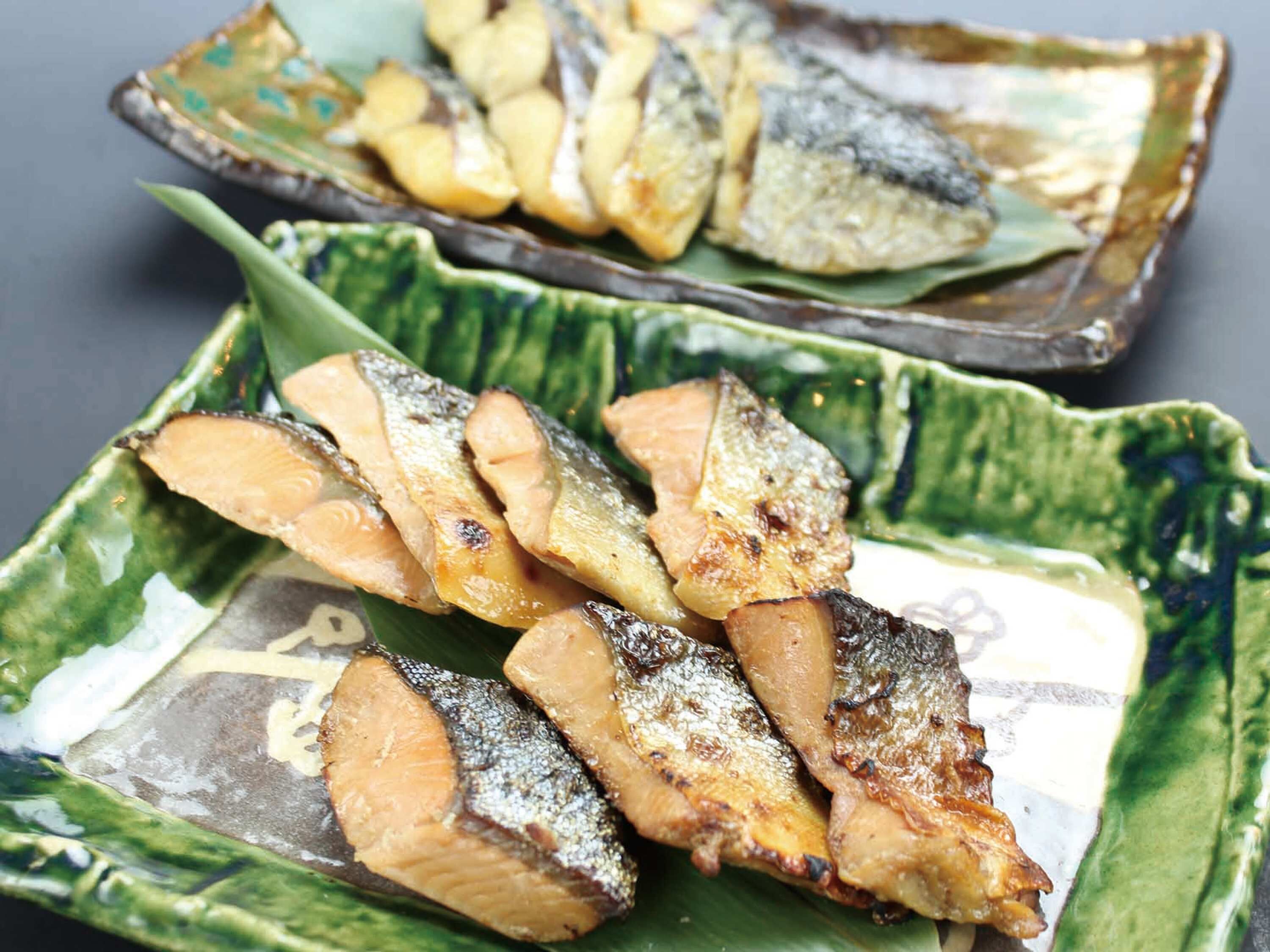 A plate of grilled fish with a green patterned bowl.