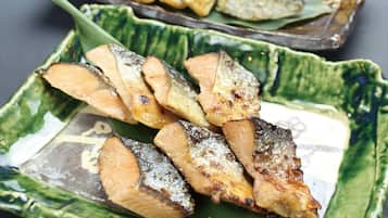 A plate of grilled fish with a green patterned bowl.