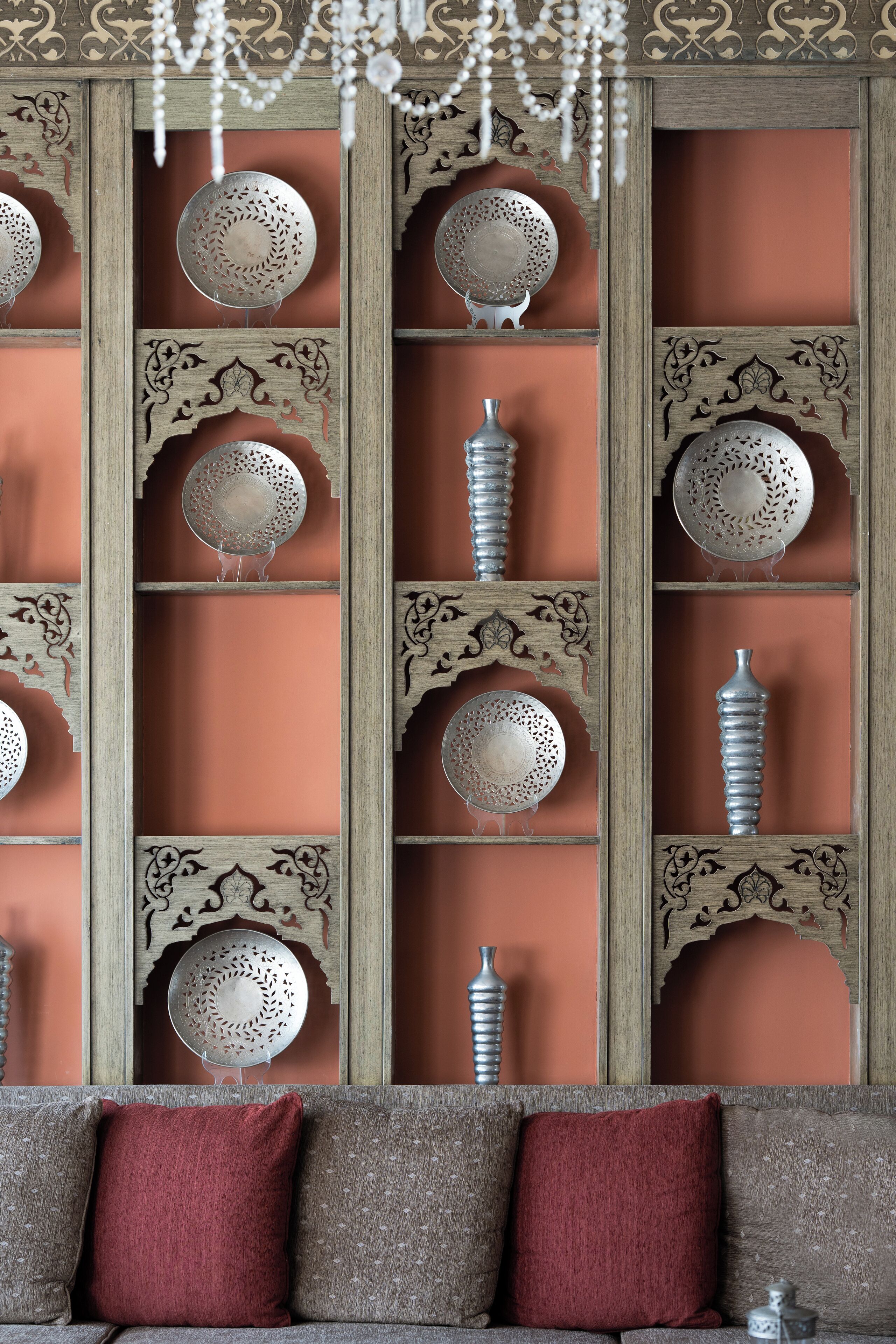 A room with a wooden partition featuring decorative metal plates and a hanging chandelier.
