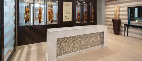A reception area with a reception desk, decorative vases, and a framed artwork on the wall.
