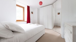 Une chambre à coucher moderne avec un grand lit, une armoire et un miroir.