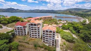 Um hotel de vários andares com telhado vermelho, cercado por vegetação e um lago.