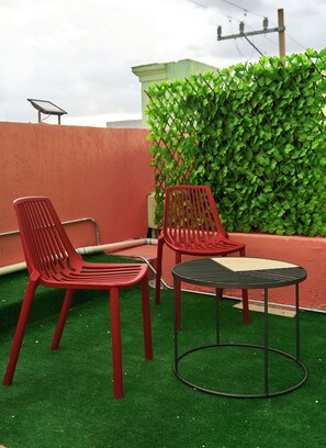A rooftop terrace with red plastic chairs and a small round table. - Nora Hotel & Co living (Guadalajara)