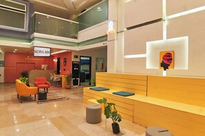 A modern lobby with a reception desk, seating area, and a UBER pickup point. - Nora Hotel & Co living (Guadalajara)