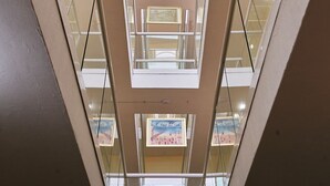 Un atrio de varios niveles con barandillas de cristal y obras de arte en las paredes.