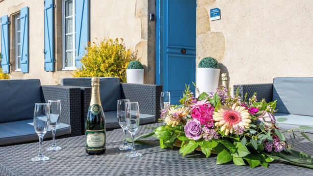 A table set with a bottle of champagne, glasses, and a floral arrangement.