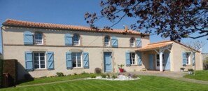 A two-story house with a tiled roof and blue shutters.