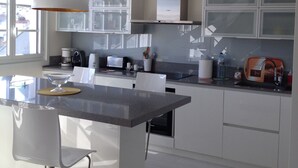 Una cucina moderna con isola centrale, mobili bianchi e un'ampia finestra che offre luce naturale.
