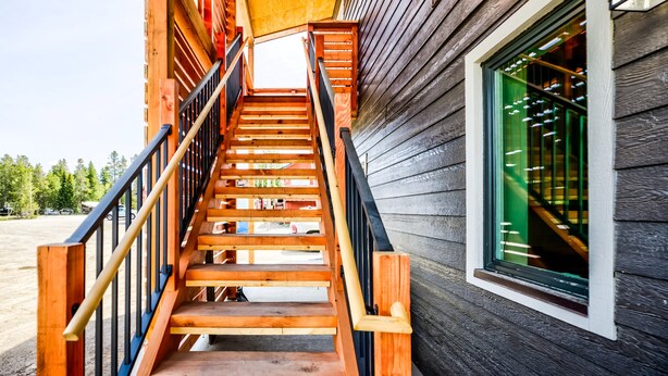 Una escalera de madera conduce a una entrada del segundo piso, con un escaparate que muestra zapatos.