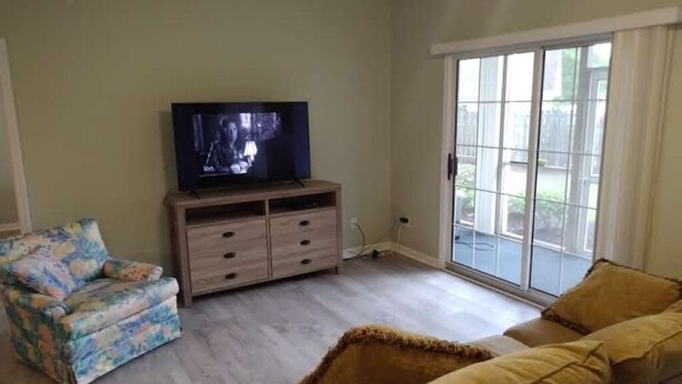 A living room with a television, a sofa, a chair, and a sliding glass door to the outside. - Nice, totally re modeled, 3 bedroom condo in the heart of Cherry Grove Beach (North Myrtle Beach)