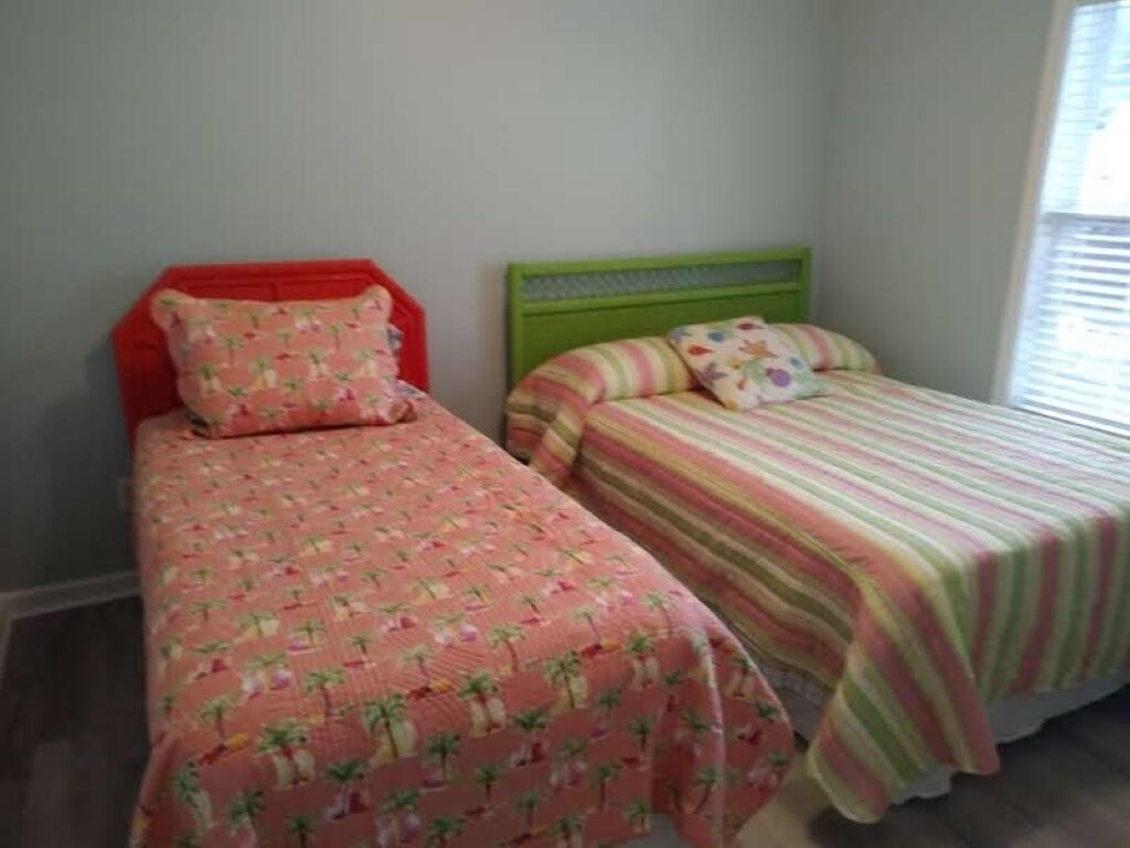Two single beds with different colored headboards and floral-patterned bedding.