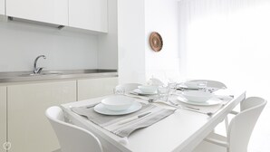 A modern kitchen with white cabinetry, a stainless steel sink, and a dining area with a white table set for four. - Rivazzurra Homes - 2 (Termoli)