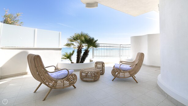 A balcony with wicker furniture, a palm tree, and a view of the sea. - Rivazzurra Homes - 2 (Termoli)