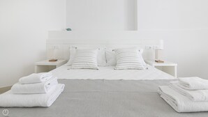 A neatly made bed with white linens and striped pillows, two bedside tables with lamps, and a clean, minimalist room design. - Rivazzurra Homes - 2 (Termoli)