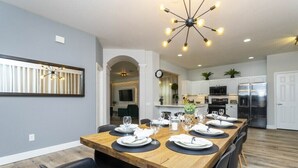 A modern kitchen with a dining area set for six. - Windsor Oasis 6BR Pool & Game Room  9 min Disney! (Kissimmee)
