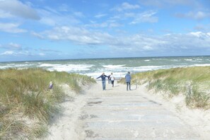 En sti der fører til stranden med folk der går.