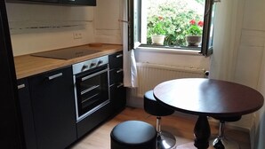 Cuina compacta amb fogó, forn i finestra amb vistes a vegetació.