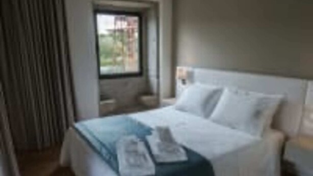 A hotel room with a bed, a window, and a curtain.
