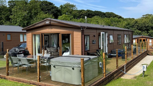 A mobile home with a patio area, a hot tub, and a deck.