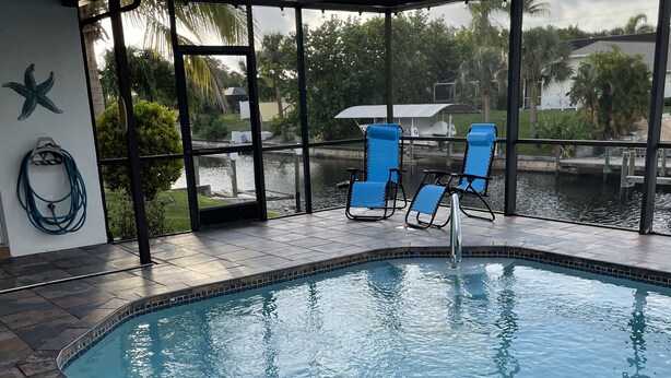 A swimming pool with blue chairs and a starfish decoration. - Love Water? Gulf Access, Boat Dock, Private Heated Pool in Lanai. (Cape Coral)