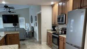 A modern kitchen with granite countertops, stainless steel appliances, and wooden cabinets. - Love Water? Gulf Access, Boat Dock, Private Heated Pool in Lanai. (Cape Coral)