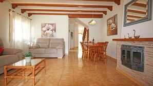 Un salon comprenant un canapé, une table à manger avec des chaises, une table basse, une cheminée et un grand miroir au mur.