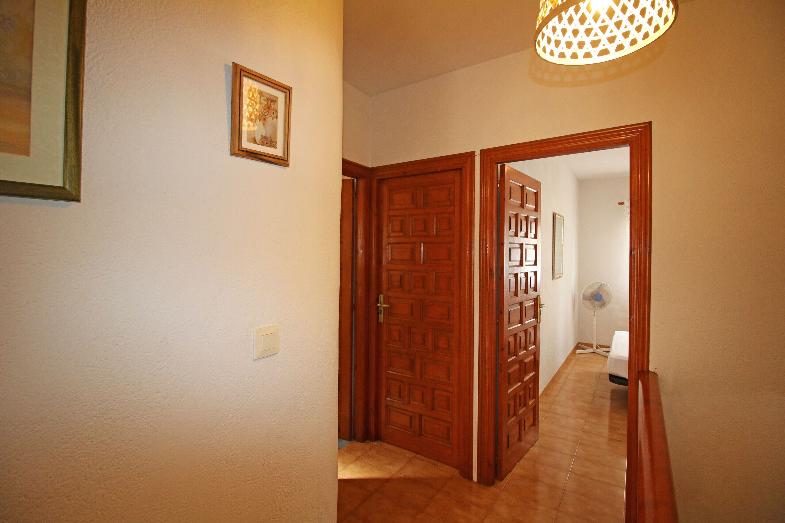 A hallway with wooden doors, a ceiling fan, and a framed picture on the wall.