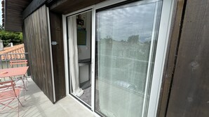 A balcony with a sliding glass door, a small table, and a chair. - Cozy chef's'apartment in Hyper center... (Andernos-les-Bains)