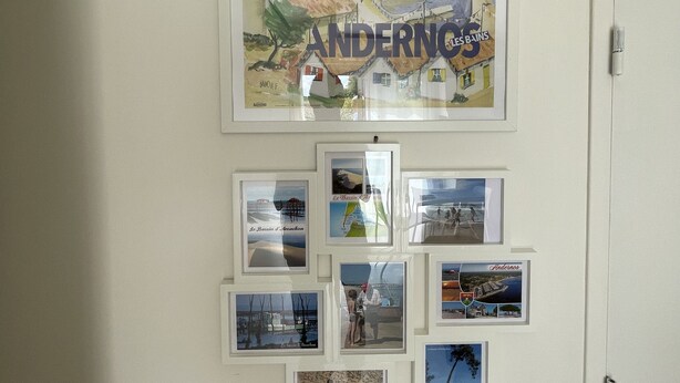 A wall with a large poster of Andernos and several smaller framed photos. - Cozy chef's'apartment in Hyper center... (Andernos-les-Bains)