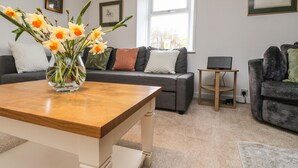 A modern living room with a sofa, a coffee table, and a laptop on a side table. - Storkery Cottage (Aberdeen)