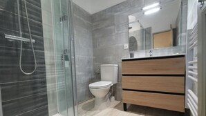 A modern bathroom with a glass shower enclosure, a toilet, and a wooden vanity with a mirror. - Maison Gasconne, Charme de L'ancien Allié au Confort du Moderne ! (Saint-Jean-le-Comtal)