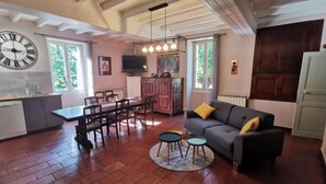 A spacious living area with a dining table, sofa, and a kitchen area with a sink and cabinets. - Maison Gasconne, Charme de L'ancien Allié au Confort du Moderne ! (Saint-Jean-le-Comtal)