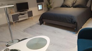 Quarto com uma cama, televisão, escrivaninha e cadeira.