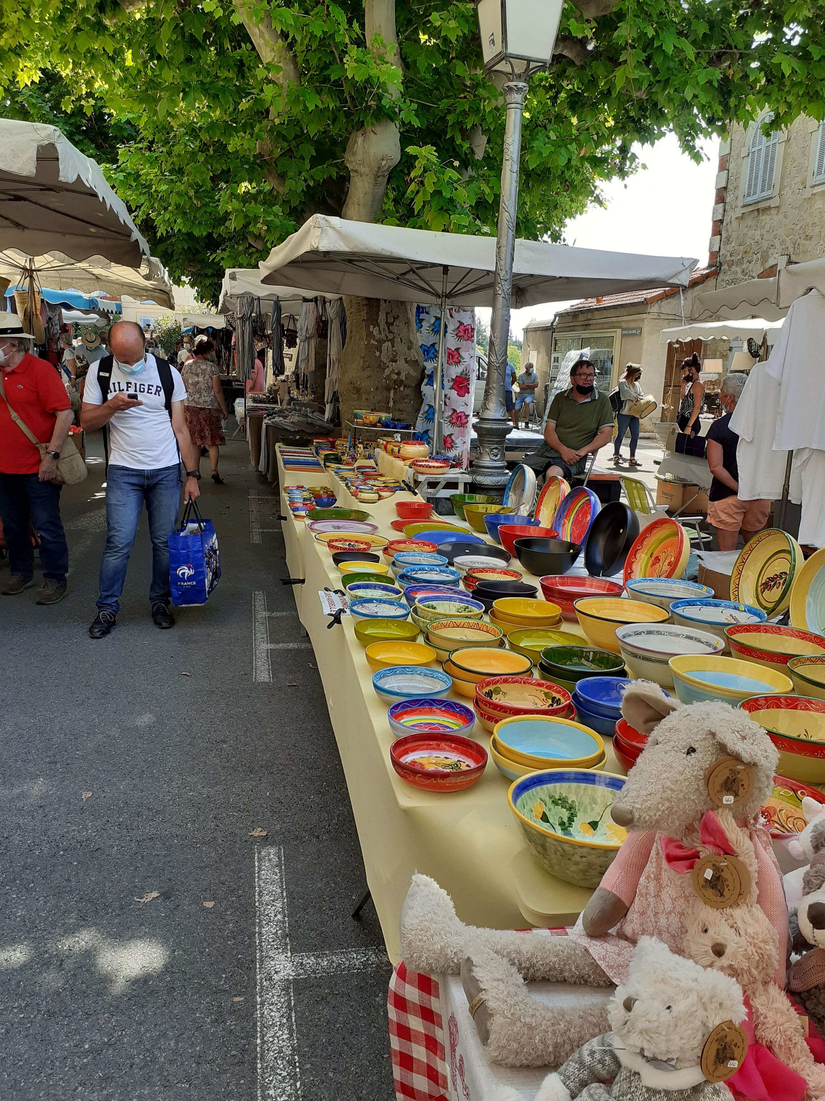A market stall with various colorful bowls and a teddy bear.