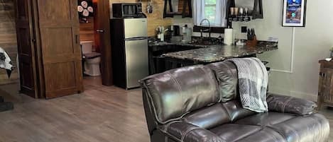Un salón amplio con un sofá de cuero, una cocina con electrodomésticos modernos y un techo de madera.