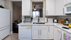 Una cocina moderna con armarios blancos, lavavajillas integrado, un fregadero y una estufa.
