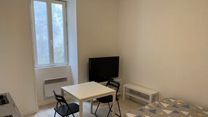 A small, clean room with a bed, a desk, a chair, a TV, and a window. - Studio Proche Centre Ville (Bayonne)