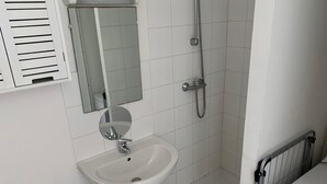 A bathroom with a white sink, a mirror, a shower, and a radiator. - Studio Proche Centre Ville (Bayonne)