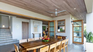 Un comedor amplio con una mesa y sillas de madera, un ventilador de techo y vistas al exterior.