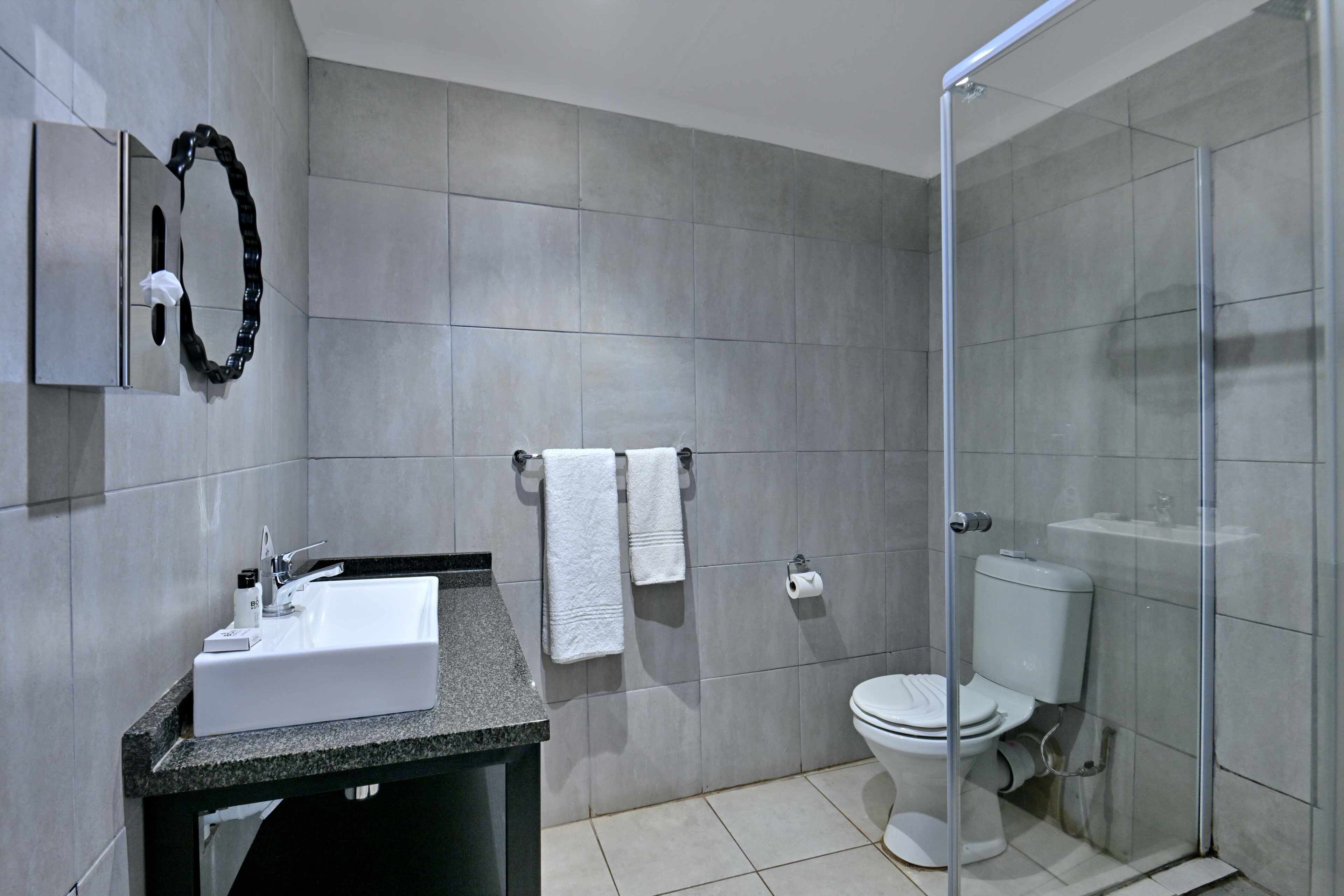 A modern bathroom with a sink, toilet, and shower.