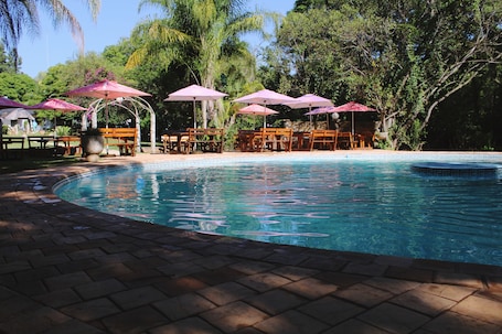 Una piscina techada, una piscina al aire libre, sombrillas